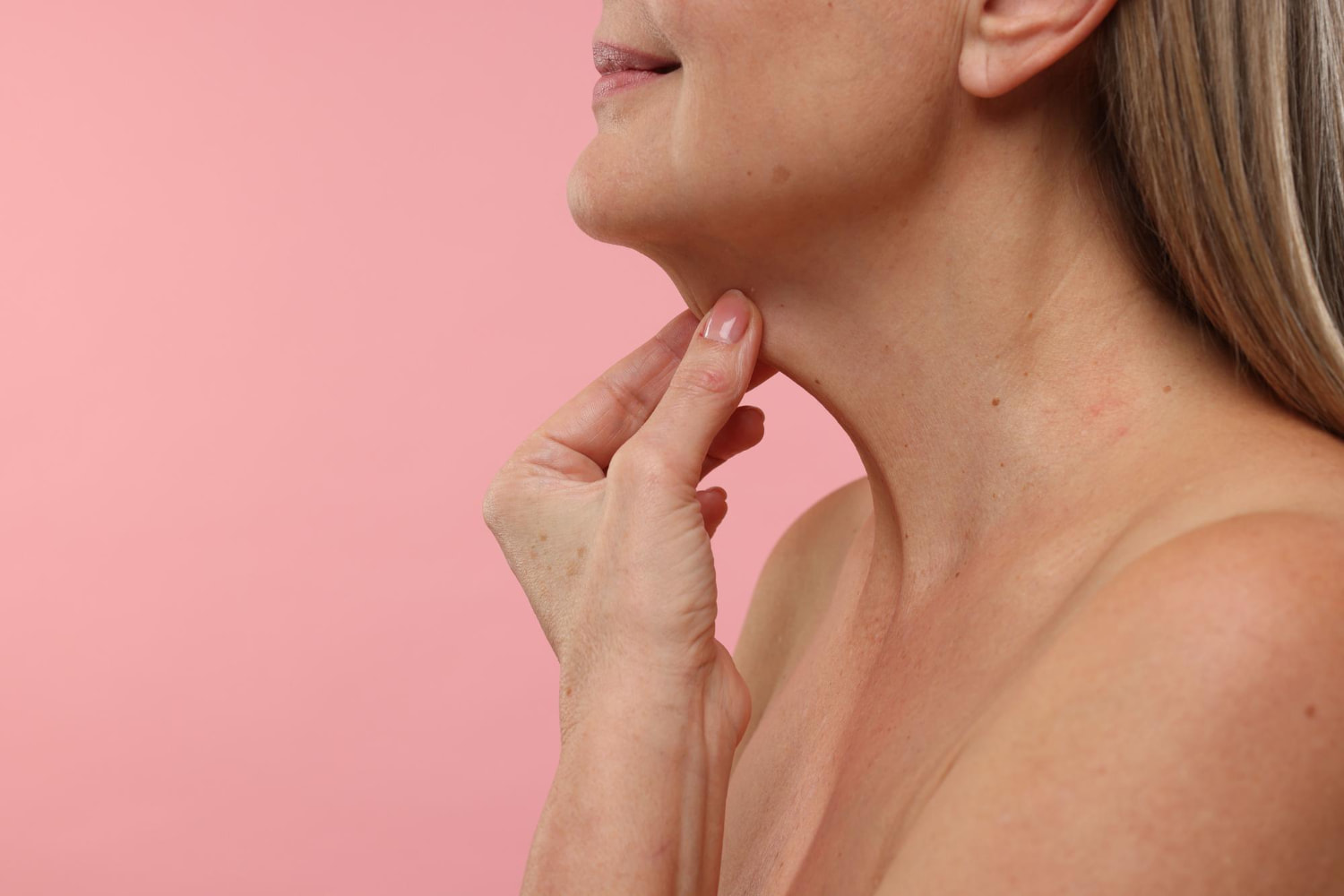 Mulher madura tocando seu pescoço onde deseja fazer lifting cervical