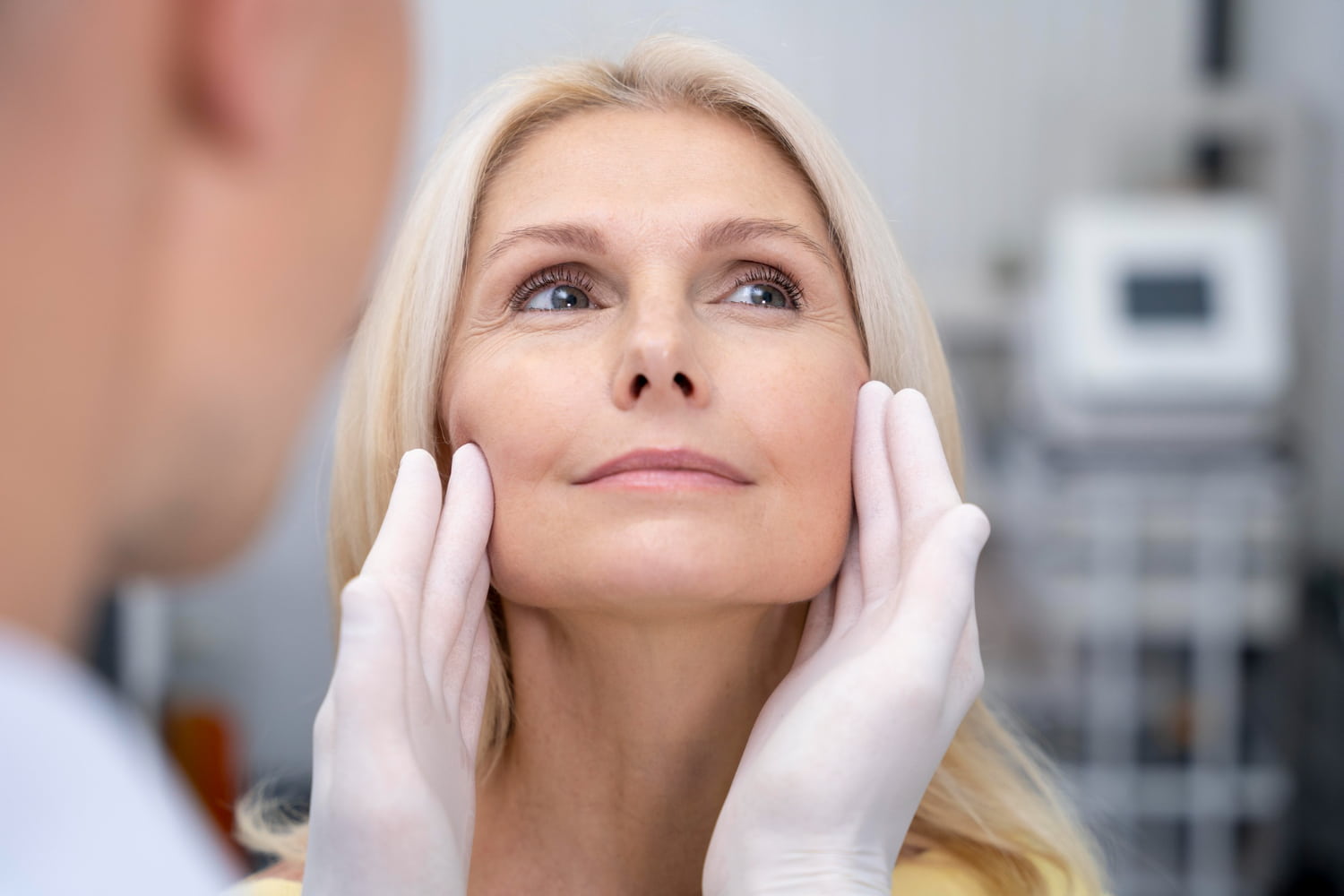 Médico avaliando rosto de paciente madura antes de fazer lifting facial
