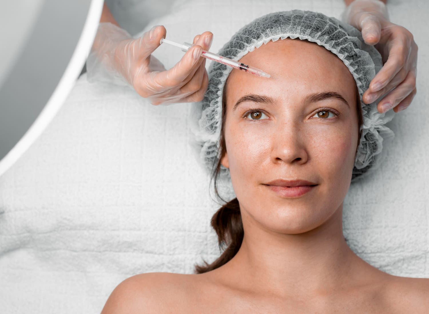 Médico aplicando injeção de preenchimento facial em paciente feminina